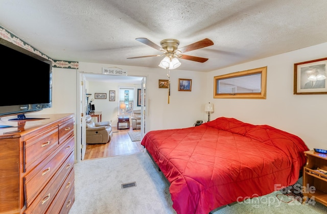 bedroom featuring ceiling fan, light hardwood / wood-style floors, and a textured ceiling