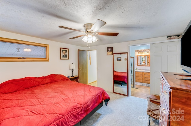 bedroom featuring light carpet, a textured ceiling, ensuite bathroom, and ceiling fan