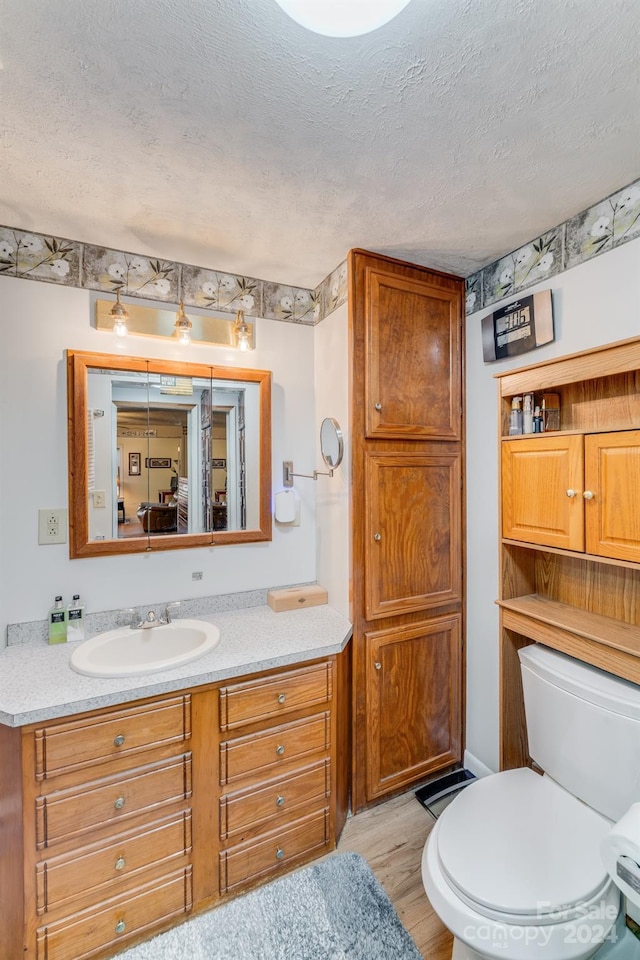 bathroom featuring vanity, wood-type flooring, a textured ceiling, and toilet