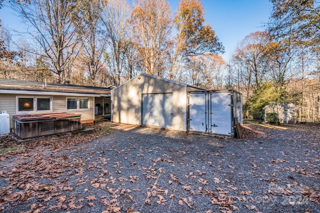 view of outdoor structure featuring central air condition unit, a hot tub, and a garage