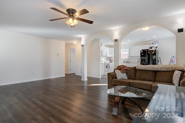 living room featuring ceiling fan and dark wood-type flooring