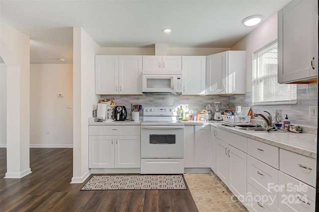 kitchen featuring sink, dark wood-type flooring, white appliances, decorative backsplash, and white cabinets