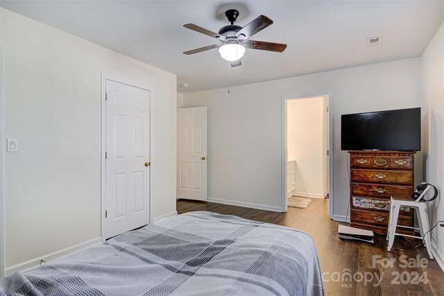 bedroom with ceiling fan, ensuite bathroom, and dark wood-type flooring