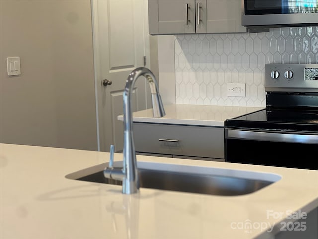 kitchen with white cabinets, electric stove, backsplash, light countertops, and a sink