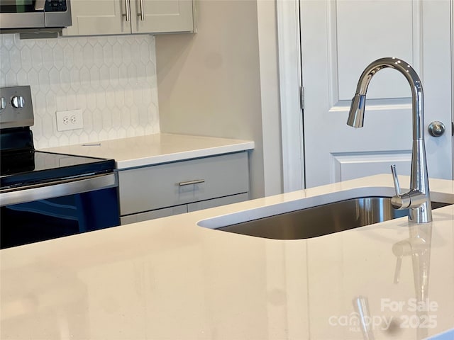 kitchen featuring light countertops, backsplash, stainless steel electric range, and a sink