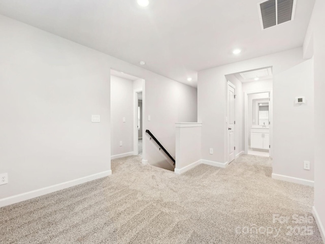 unfurnished room featuring recessed lighting, light colored carpet, visible vents, baseboards, and attic access