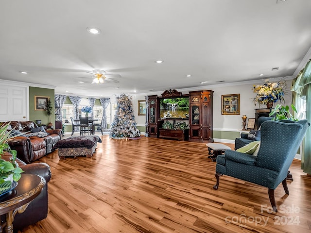 living room featuring ceiling fan, light wood-type flooring, and ornamental molding