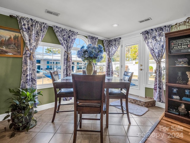 tiled dining area with crown molding and plenty of natural light