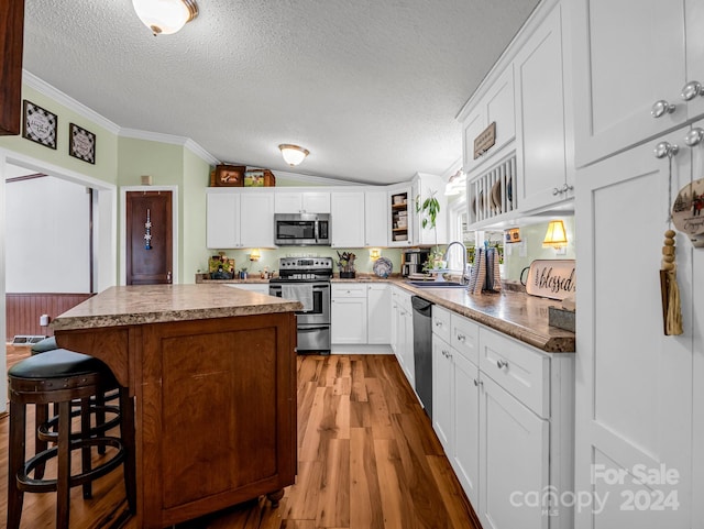 kitchen featuring hardwood / wood-style floors, a center island, white cabinetry, and appliances with stainless steel finishes