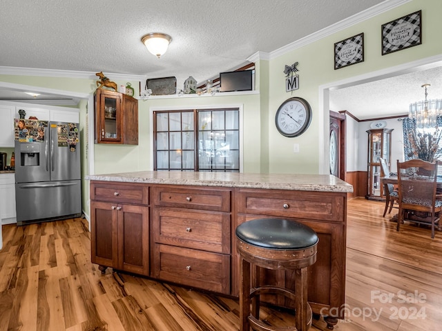 kitchen featuring crown molding, stainless steel fridge, a textured ceiling, light hardwood / wood-style floors, and light stone counters