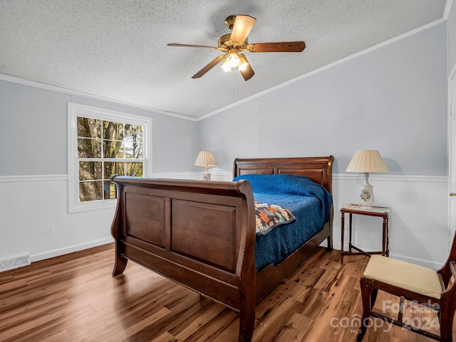 bedroom featuring wood-type flooring, a textured ceiling, ceiling fan, and crown molding