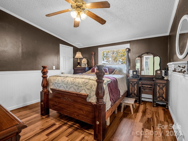 bedroom featuring a textured ceiling, ceiling fan, crown molding, hardwood / wood-style floors, and lofted ceiling