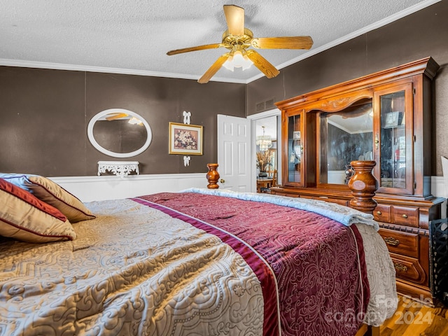 bedroom featuring a textured ceiling, hardwood / wood-style flooring, ceiling fan, and crown molding