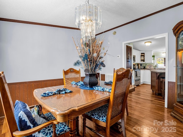 226 Mcswain Rd, Forest City, NC 28043 - dining area featuring a chandelier, a textured ceiling, wood finished floors, wainscoting, and crown molding
