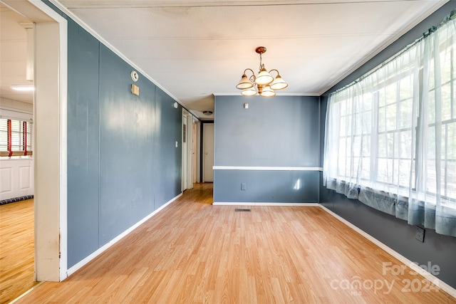 empty room with a chandelier, hardwood / wood-style floors, and ornamental molding