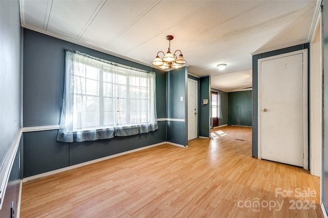 unfurnished room featuring light hardwood / wood-style flooring, a chandelier, and a textured ceiling