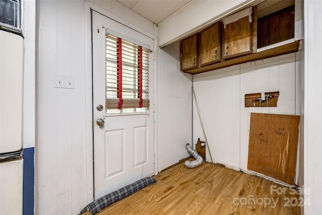 washroom featuring wood walls, light hardwood / wood-style floors, and cabinets