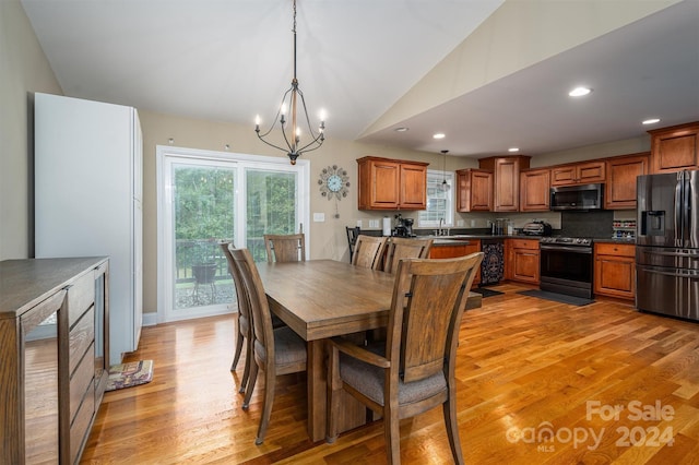 dining area with sink, light hardwood / wood-style floors, vaulted ceiling, and a notable chandelier