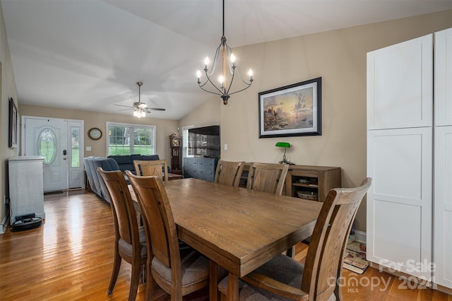 dining room with ceiling fan with notable chandelier, light wood-type flooring, and lofted ceiling