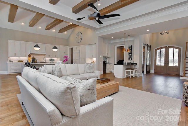 living room with beam ceiling, ceiling fan, french doors, high vaulted ceiling, and light wood-type flooring