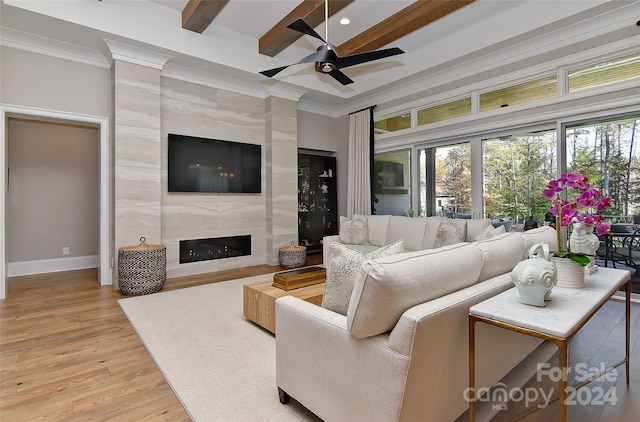 living room featuring beam ceiling, ceiling fan, a fireplace, and light hardwood / wood-style floors