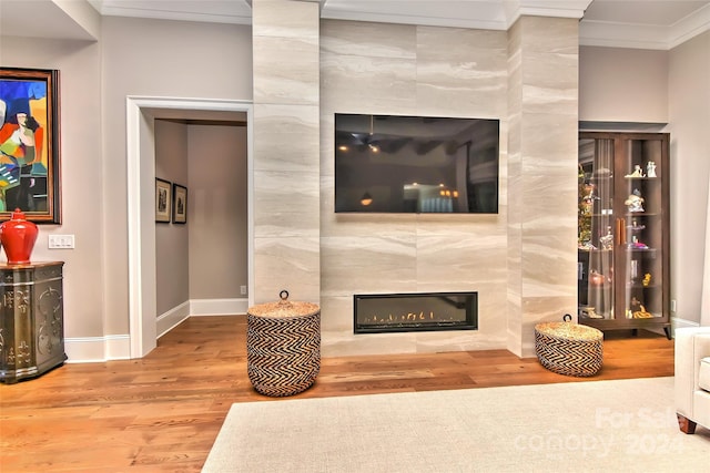 living room featuring hardwood / wood-style floors, tile walls, crown molding, and a tiled fireplace