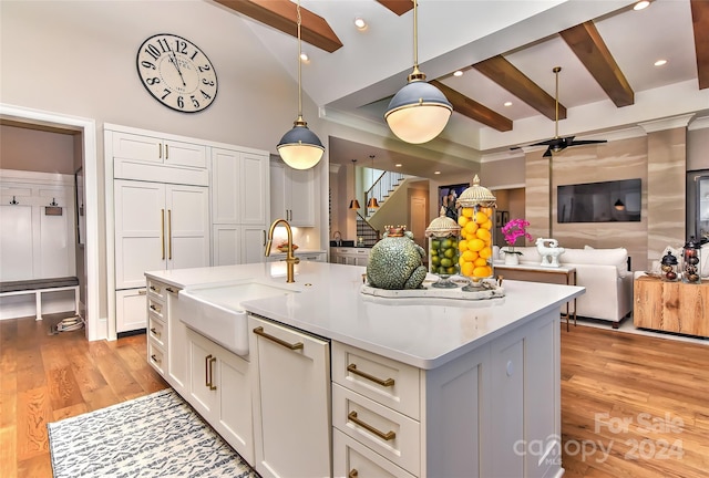 kitchen with ceiling fan, sink, light hardwood / wood-style flooring, pendant lighting, and a kitchen island with sink