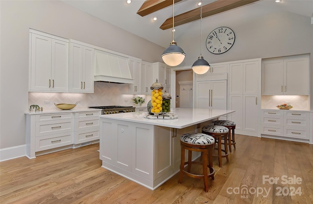 kitchen featuring premium range hood, white cabinetry, beamed ceiling, and light hardwood / wood-style floors