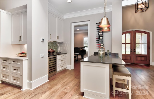 kitchen featuring white cabinetry, french doors, hanging light fixtures, beverage cooler, and light hardwood / wood-style floors