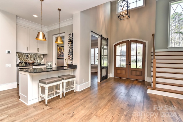 entryway with french doors, sink, a barn door, crown molding, and light wood-type flooring