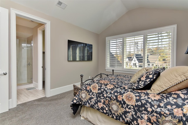 bedroom featuring light carpet, connected bathroom, and lofted ceiling