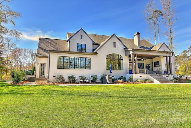 back of house with ceiling fan and a yard