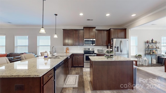 kitchen featuring stainless steel appliances, a healthy amount of sunlight, dark wood-type flooring, sink, and pendant lighting