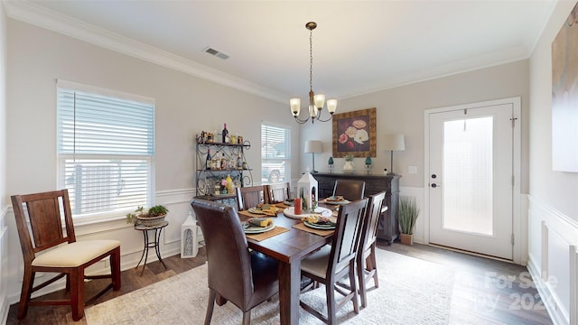 dining room featuring plenty of natural light, ornamental molding, a notable chandelier, and light hardwood / wood-style flooring