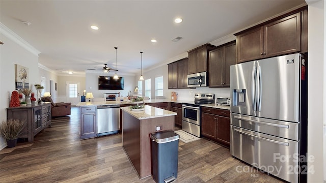 kitchen featuring dark wood-type flooring, crown molding, decorative light fixtures, kitchen peninsula, and stainless steel appliances