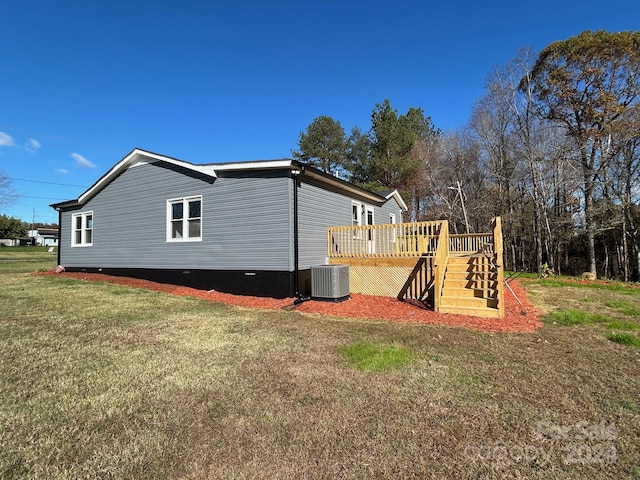 view of side of home with central air condition unit, a lawn, and a wooden deck