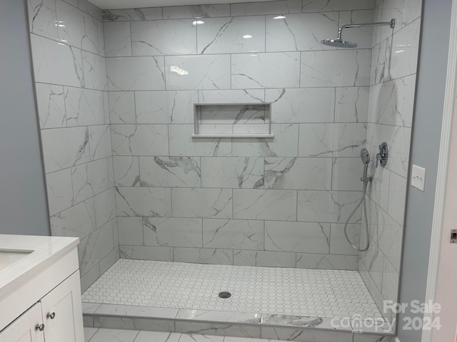 bathroom featuring a tile shower and vanity