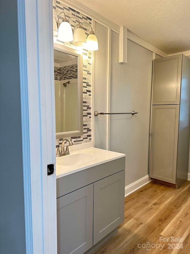 bathroom with vanity, hardwood / wood-style floors, a textured ceiling, and walk in shower