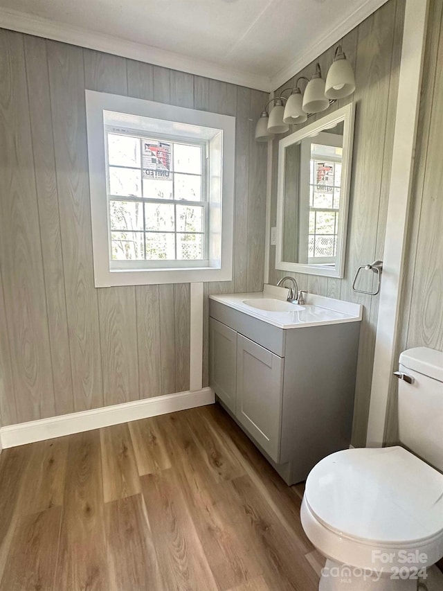 bathroom featuring ornamental molding, vanity, wooden walls, hardwood / wood-style floors, and toilet