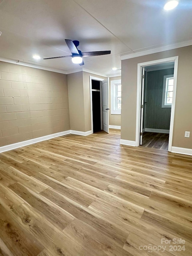 unfurnished bedroom featuring ceiling fan, crown molding, multiple windows, and light hardwood / wood-style flooring