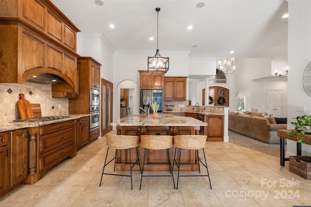 kitchen featuring light stone countertops, a notable chandelier, an island with sink, a breakfast bar, and appliances with stainless steel finishes