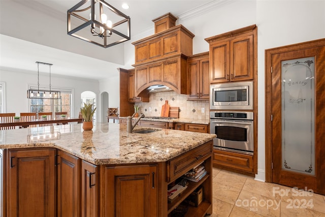 kitchen with light stone countertops, sink, pendant lighting, a kitchen island with sink, and appliances with stainless steel finishes