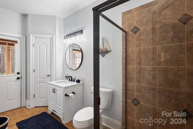 bathroom featuring tile patterned flooring, vanity, toilet, and tiled shower