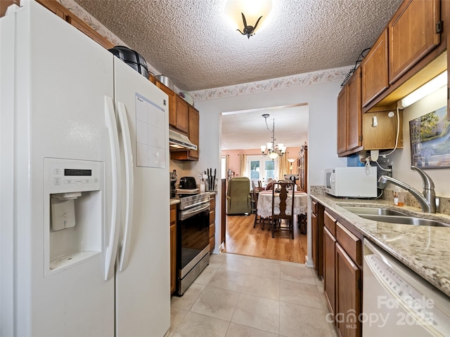 kitchen featuring stainless steel appliances, sink, pendant lighting, light tile patterned floors, and an inviting chandelier