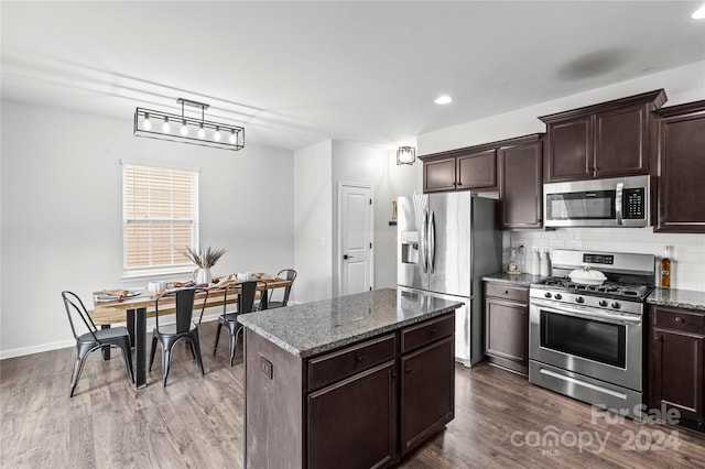 kitchen with a center island, dark wood-type flooring, stainless steel appliances, dark stone counters, and dark brown cabinets