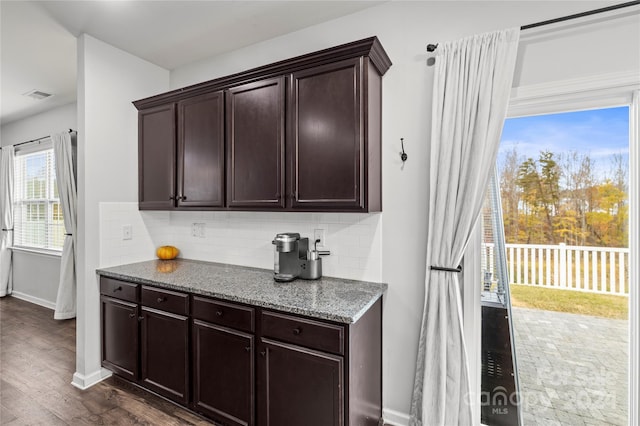 kitchen featuring backsplash, stone countertops, dark brown cabinetry, and dark wood-type flooring