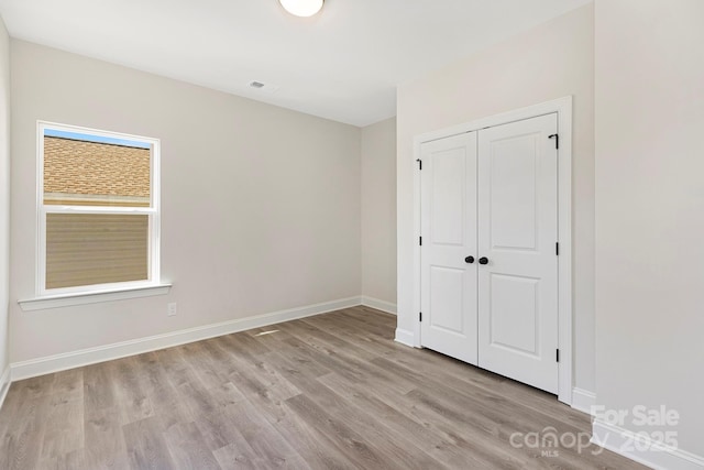 unfurnished bedroom featuring light hardwood / wood-style flooring and a closet