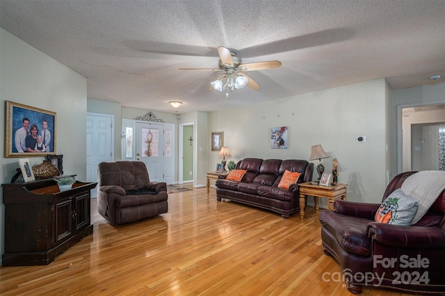 living room with ceiling fan, a textured ceiling, and light hardwood / wood-style flooring