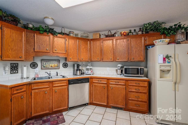 kitchen with a textured ceiling, sink, stainless steel appliances, and tile countertops