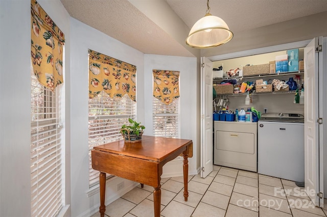 laundry area featuring washing machine and dryer, light tile patterned floors, and a textured ceiling